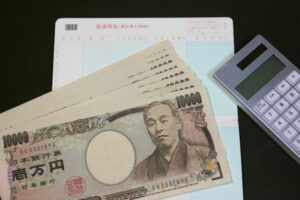 銀行通帳と1万円札と電卓